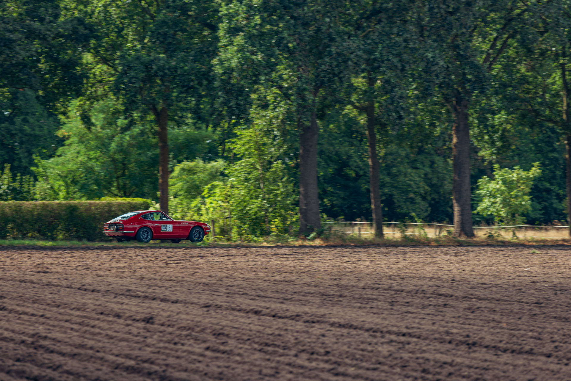 Rode Datsun 240Z langs de akkers van Zuid-Nederland